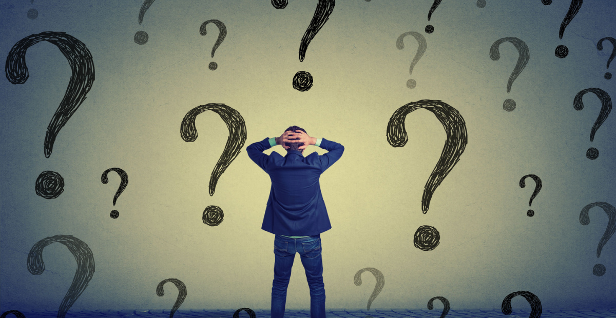 Man holds head amid question marks
