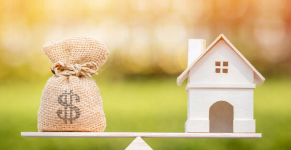 Money bag balanced against home