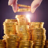 Gold coins being stacked with a hand taking some away
