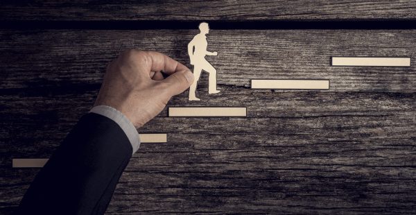 Man holding cut-out of man climbing steps